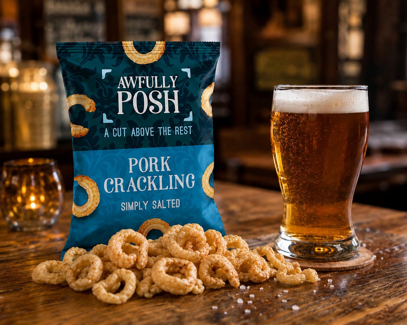 Awfully Posh Pork Scratchings styled on a pub bartop with a glass of British ale, scratchings spilling out of the pack